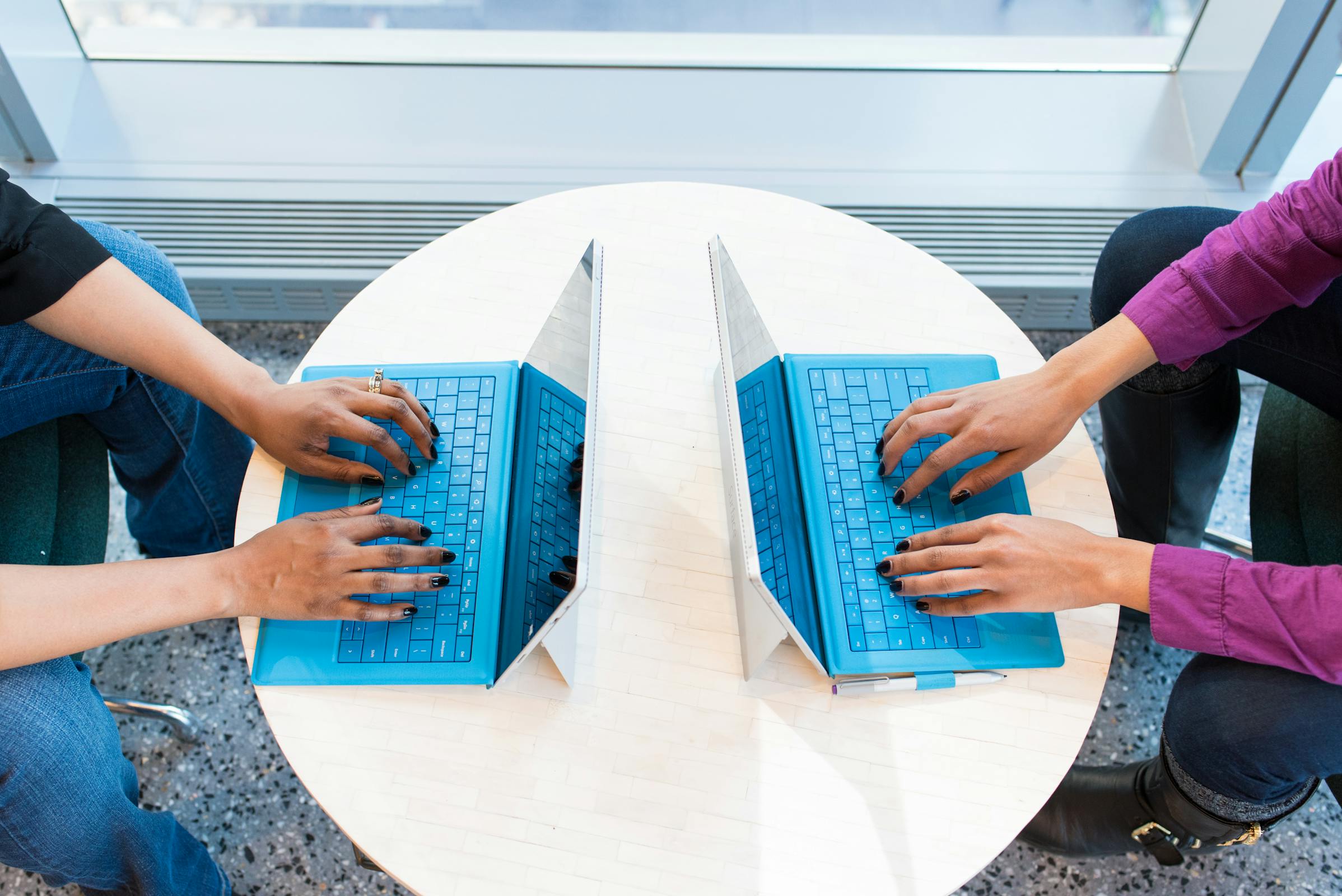 A boy and a girl typing on the laptop