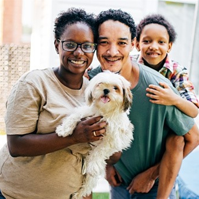 A family of three holding a dog