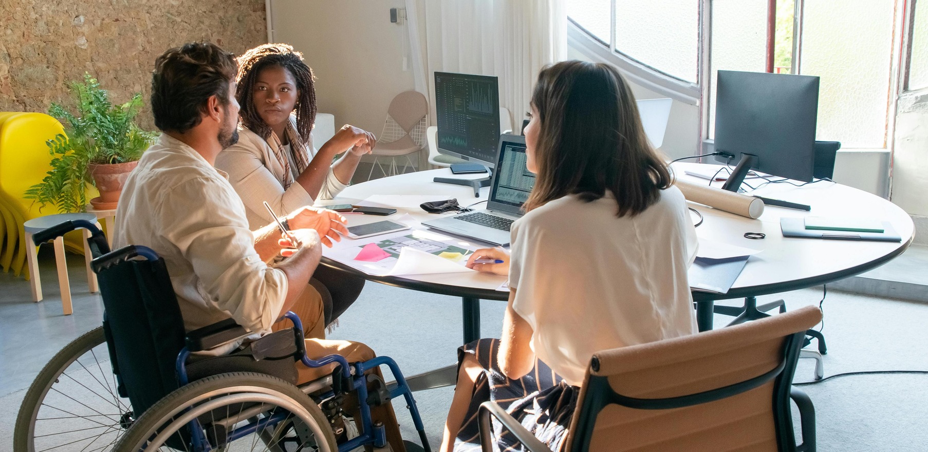 Group of diverse individuals with a man in wheelchair looking at computer