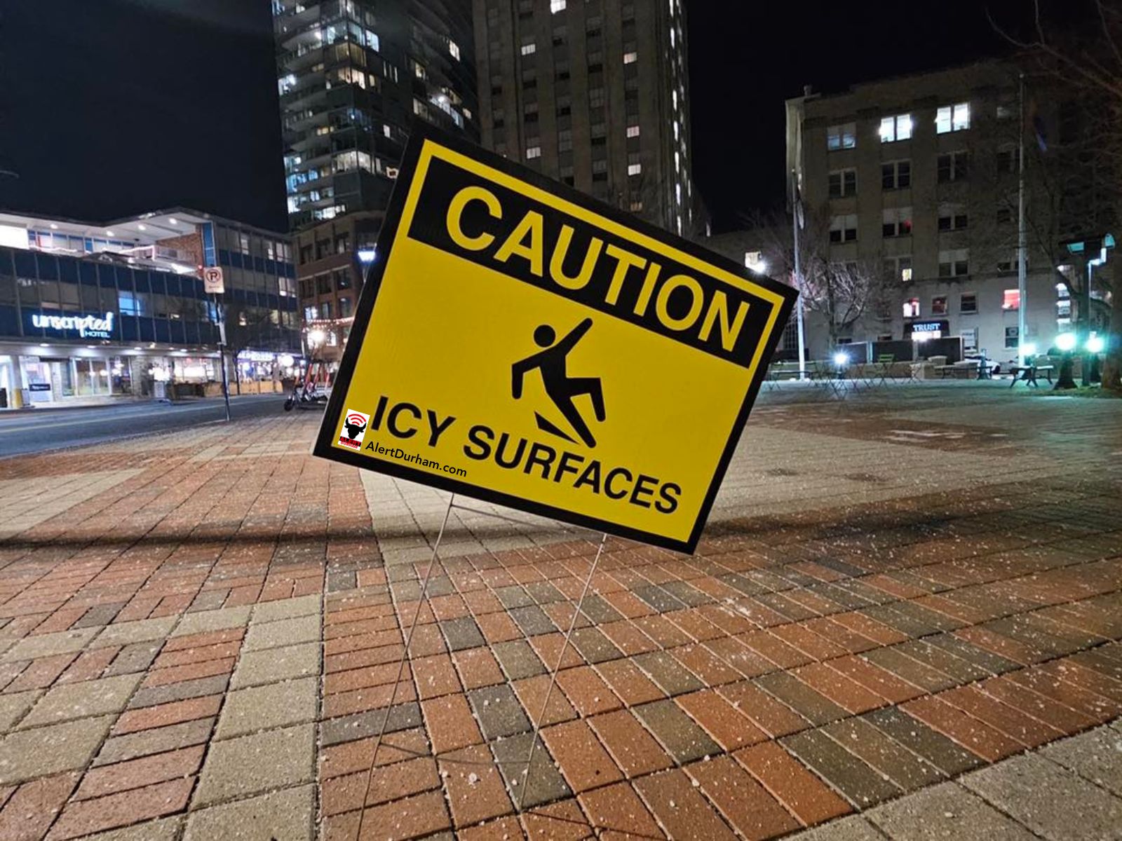 Icy surfaces sign on sidewalk in downtown Durham. Salt pellets are all over the ground.