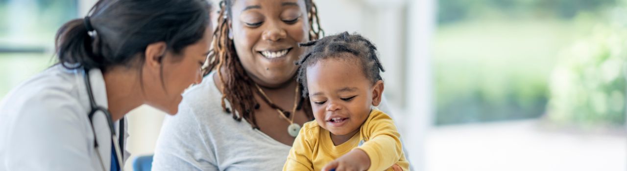 A mother smiles as her child plays in doctor's office.