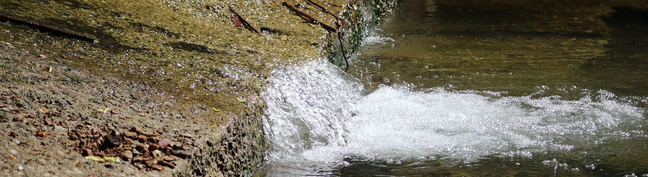 Water running along concrete into a pool of water.
